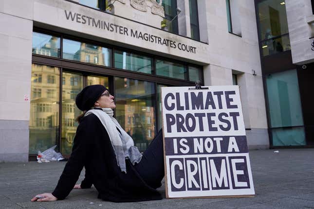 A protester sits outside Westminster Magistrates Court in London, Thursday, Feb. 1, 2024. Climate activist Greta Thunberg is on trial for protesting outside a major oil and gas industry conference in London last year. (AP Photo/Alberto Pezzali)