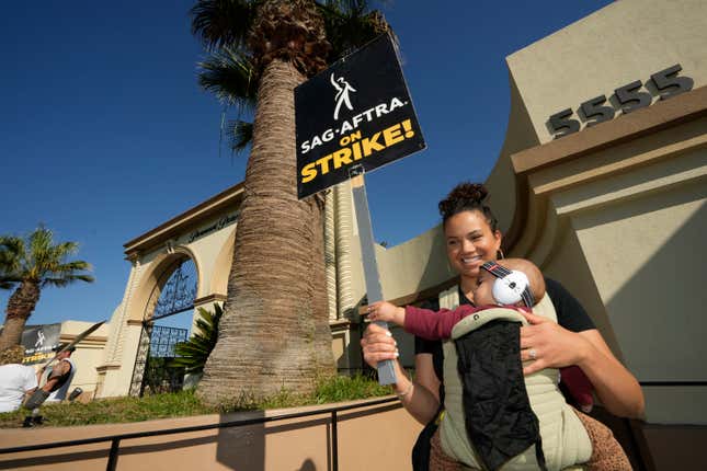 Actor Michele Weaver and her daughter join demonstrators outside the Paramount Pictures Studio in Los Angeles, Tuesday, Sept. 26, 2023. Actors are still on strike with no talks planned. But the tentative writers deal announced Sunday night may provide momentum that could lead to a resolution for them too. (AP Photo/Damian Dovarganes)