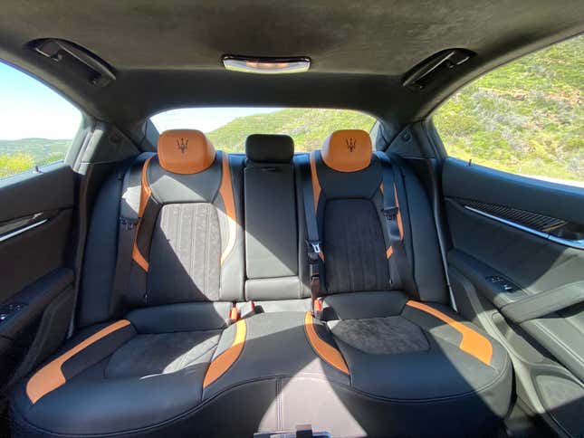 A photo of the rear seats with the Maserati trident embroidered on the outboard terra cotta leather headrests
