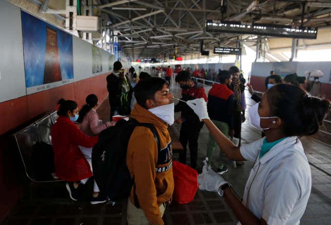 A health worker takes a swab sample of a passenger entering the city to test for COVID-19 at a railway station in Ahmedabad, India, Friday, Dec. 3, 2021. India on Thursday confirmed its first cases of the omicron coronavirus variant in two people and officials said one arrived from South Africa and the other had no travel history. A top medical expert urged people to get vaccinated.