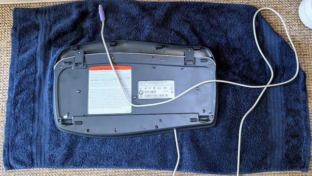 A dead keyboard, lying on its belly on a towel.