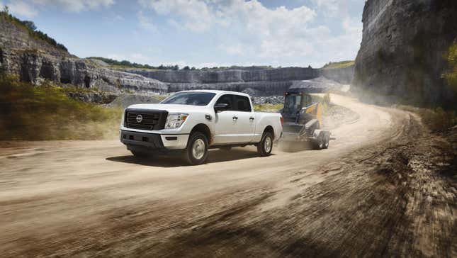 A white Nissan Titan towing equipment through a quarry