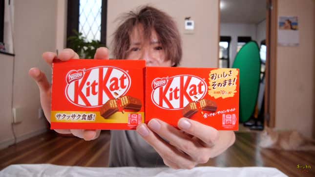 A YouTuber holds up two packages of Kit-Kats, one of which is smaller. 