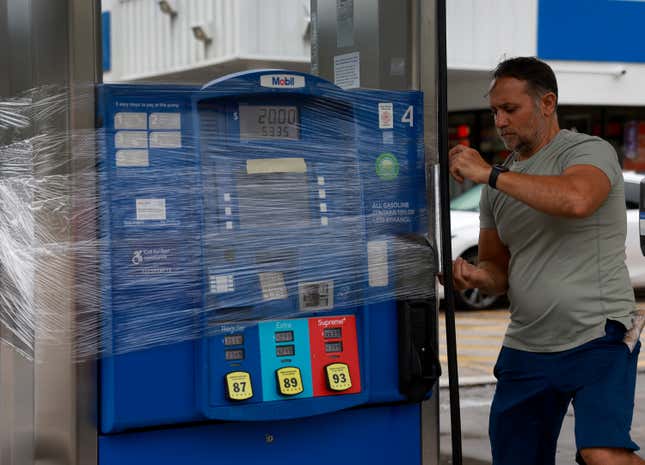 Nazih Tageddine wraps cellophane around his gas pump to prevent it from being damaged by the rain from Hurricane Idalia as it passes offshore on August 29, 2023 in Clearwater Beach, Florida.