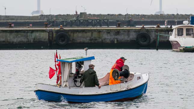 A small fishing boat approaches a port. 