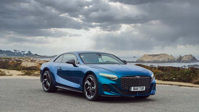 A blue Bentley Batur is parked in front of the sea under dark gray clouds