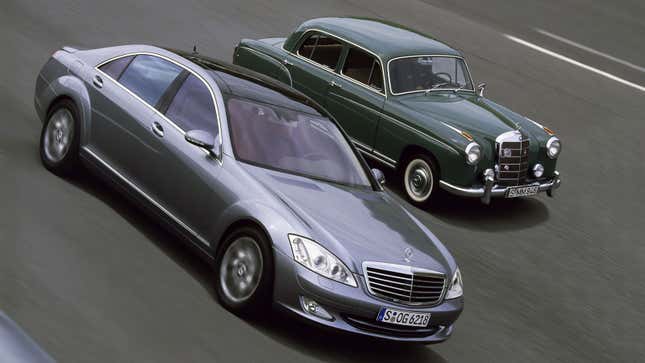 A photo of a new and old Mercedes S Class sedan driving side by side on a road. 