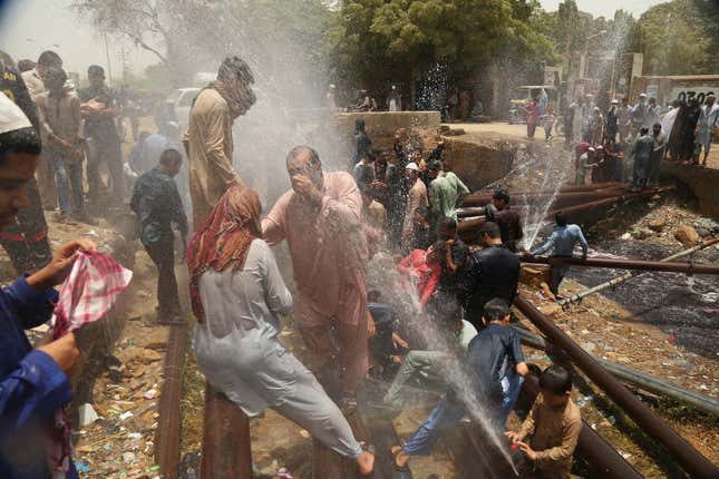 People cool off around punctured water supply lines in Karachi.