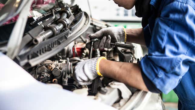 A person works on the engine bay of a car