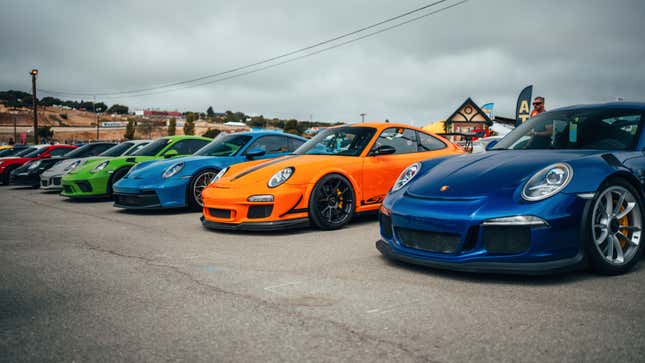 A line of several generations of Porsche 911 GT3 and RS models are parked on pavement