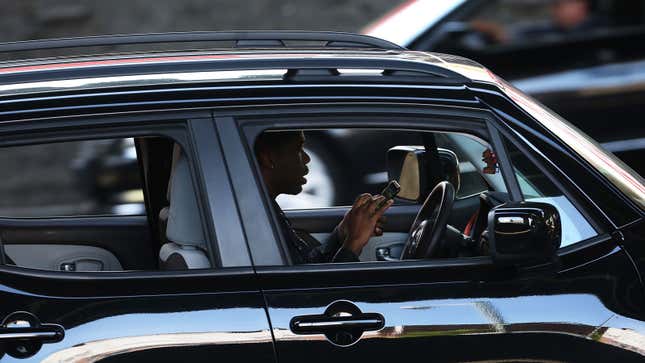 Ein Foto von jemandem, der während der Fahrt sein Telefon benutzt. 