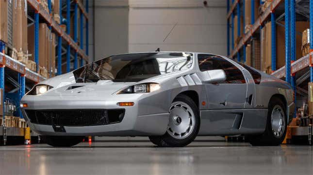 A silver Isdera Imperator 108i in a warehouse.