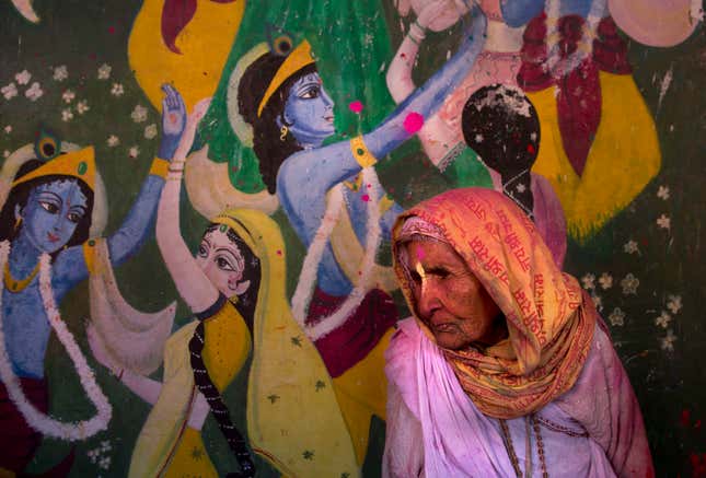 An Indian widow walks past the painting of Lord Krishna and his concert Radha during Holi, the arrival of spring festival at the Gopinath temple in Vrindavan, March 9. (AP Photo /Manish Swarup)