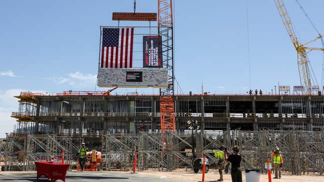 Construction workers lift a track safety barrier signed by executives to the top of the Las Vegas Grand Prix paddock building during a topping out event on April 13, 2023 in Las Vegas, Nevada