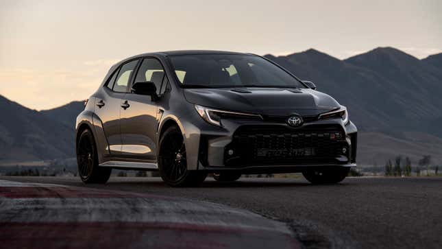 A photo of a black GR Corolla hatchback on track. 