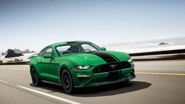 A photo of a bright green Ford Mustang driving down a coastal road. 