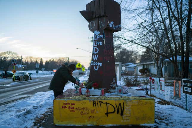 Michelle Filkins cleans up and lights candles at the Daunte Wright memorial after guilty verdicts were announced against former Brooklyn Police officer Kimberly Potter on Thursday, Dec. 23, 2021, in Brooklyn Center, Minn.