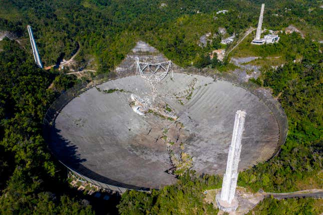 Aerial view showing extensive damage to the large radar dish, as well as the position of the fallen instrument platform. The collapse also ripped off the tops of the three support towers. 