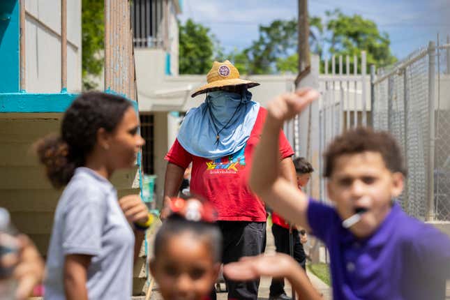 A school maintenance worker wears sun protection at the Escuela Elemental Santiago Iglesias Pantín school in San Juan, Puerto Rico, Thursday, Sept. 7, 2023. Students and teachers are holding class in public schools across Puerto Rico that lack air conditioning amid record heat this year. (AP Photo/Alejandro Granadillo)