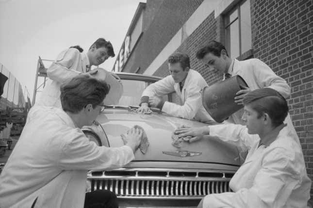 A vintage photo of a group of five young men washing a car