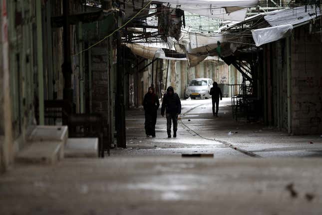 Palestinians walk down an empty street during a full strike in Hebron.