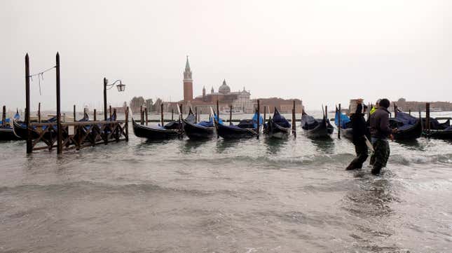 People walk on a catwalk in a flooded Saint Mark Square.