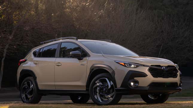 A front three quarters shot of the tan Crosstrek Hybrid parked in front of trees