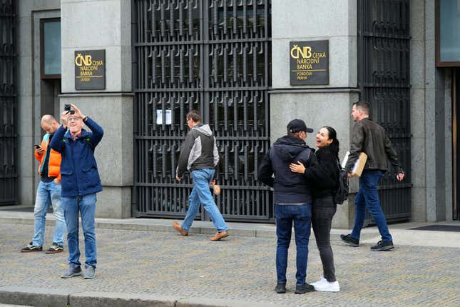 FILE - People stand outside the czech central bank in Prague, Czech Republic, on Nov. 2, 2023. On Wednesday March 20, 2024, the Czech central bank cut its key interest rate for the third straight time on amid falling inflation and an effort to help the economy. The cut by a half-percentage point brought the interest rate down to 5.75%. (AP Photo/Petr David Josek/File)