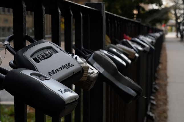 FILE - Key lock boxes for real estate showings hang on a fence outside a high-rise condominium building, Oct. 27, 2022, in Chicago. The cost of hiring a real estate agent to buy or sell a home is poised to change along with decades-old rules that have helped determine broker commissions. (AP Photo/Kiichiro Sato, File)