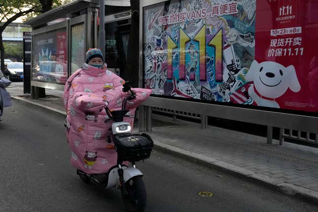 A resident rides past an advertisement for Singles&#39; Day in Beijing, Wednesday, Nov. 8, 2023. Shoppers in China have been tightening their purse strings, raising questions over how faltering consumer confidence may affect the annual Singles&#39; Day online retail extravaganza. (AP Photo/Ng Han Guan)