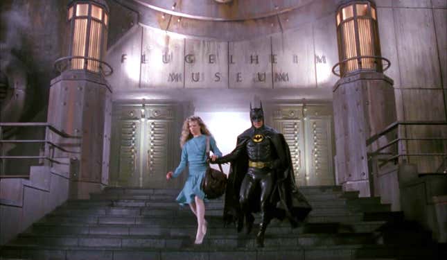 Batman runs down the steps of a museum. 