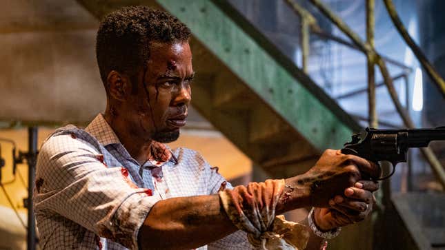 Chris Rock aims a gun while covered in blood.