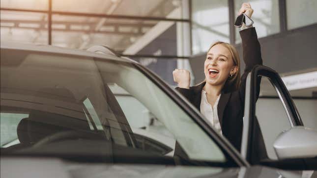 A person celebrating as they hold up a set of keys while getting into a car