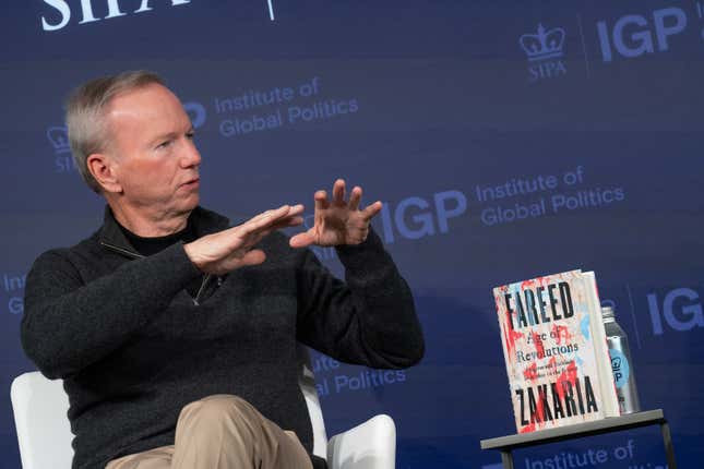 Eric Schmidt sitting in a chair talking with his hands up beside Fareed Zakaria's book in front of a navy backdrop that says "IGP Institute of Global Politics"