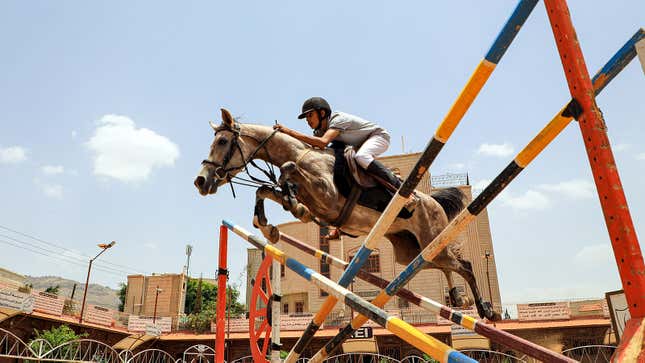 A photo of a horse and rider jumping a colorful fence. 