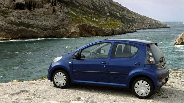 A photo of a blue Citroën C1 parked on a cliff. 
