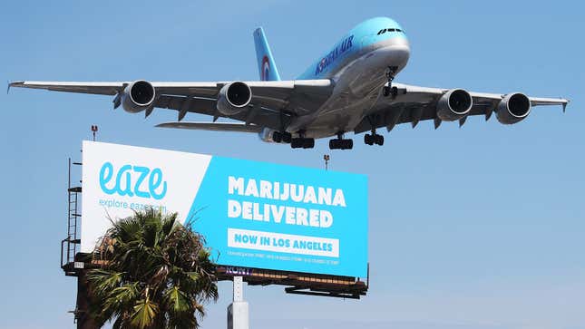 An airplane descends to land at Los Angeles International Airport above a billboard advertising the marijuana delivery service Eaze
