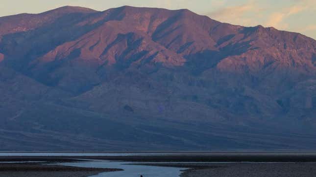 A man walks on the salt flats at dawn at Badwater, the lowest point in North America at 282 ft (86 m) below sea level, on a day that could set a new world heat record in Death Valley National Park on July 16, 2023, near Furnace Creek, California. 