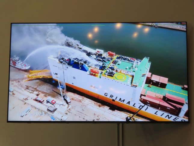 A photo displayed on a video monitor in Union,N.J., Wednesday, Jan. 10, 2024 shows a burning cargo ship in Newark N.J. on July 5, 2023. Federal investigators are conducting hearings into the blaze that killed two Newark, N.J. fire captains. (AP Photo/Wayne Parry)