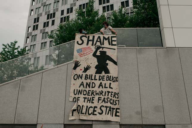 Demonstrators denouncing systemic racism in law enforcement hang a banner criticizing New York City Mayor Bill de Blasio in the borough of Brooklyn minutes before a citywide curfew went into effect on June 4, 2020 in New York City.