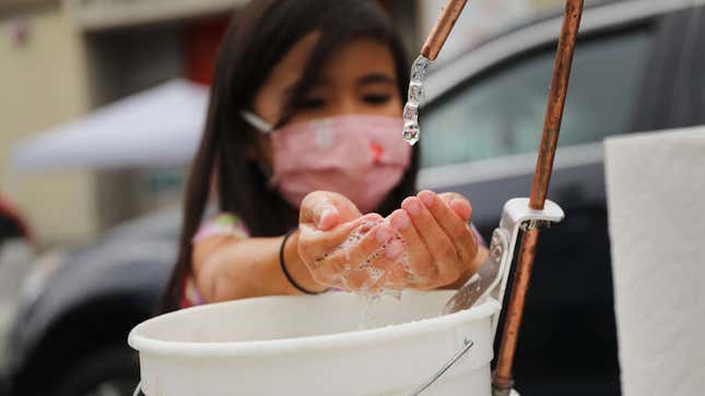 A student washes her hands at the outdoor learning demonstration at Public School 15.