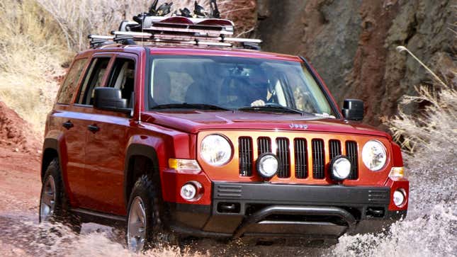 A photo of a red Jeep Patriot SUV driving through a river. 