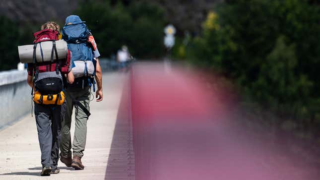 A photo of two people wearing hiking backpacks. 