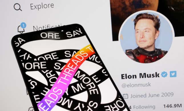 A phone with the Meta Threads app logo is held in front of Elon Musk's Twitter account page