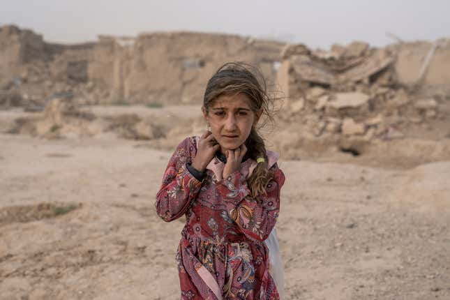 FILE - An Afghan girl carries donated aid to her tent, while she is scared from the fierce sandstorm, after an earthquake in Zenda Jan district in Herat province, western of Afghanistan, Oct. 12, 2023. Human Rights Watch said Monday, Feb. 12, 2024 that Afghanistan’s public health system has been hit hard following a sharp reduction in foreign assistance, coupled with serious Taliban abuses against women and girls, jeopardizing the right to healthcare of millions of Afghans. (AP Photo/Ebrahim Noroozi, File)