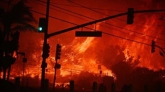 Un incendie brûle en arrière-plan d’une rue de Los Angeles. 