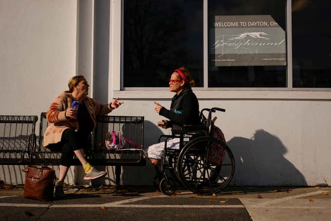 Tina Fontaine, left, and Tina Green talk as they wait for a bus outside the entrance to the Greyhound&#39;s Dayton Trotwood Bus Station in Dayton, Ohio, Wednesday, Nov. 22, 2023. Green is en route to St. Louis. Despite inflation and memories of past holiday travel meltdowns, millions of people are expected to hit airports and highways in record numbers over the Thanksgiving Day break. (AP Photo/Carolyn Kaster)