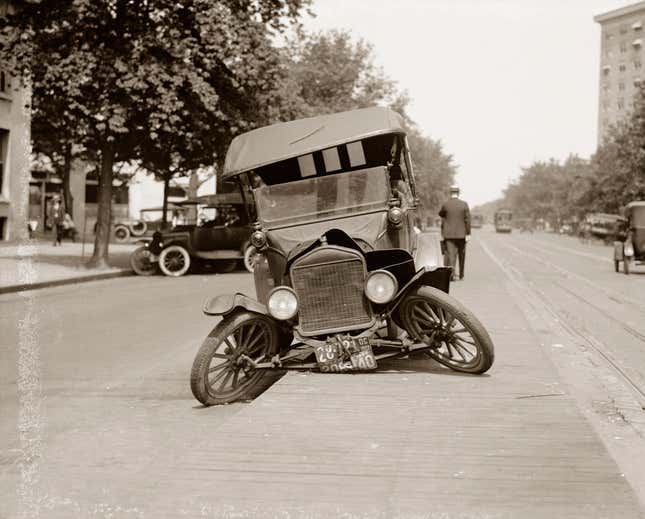 Humorous view of a wrecked 1920s car in Washington DC, sitting in the street with its tires splayed awkwardly (silver print), c 1920