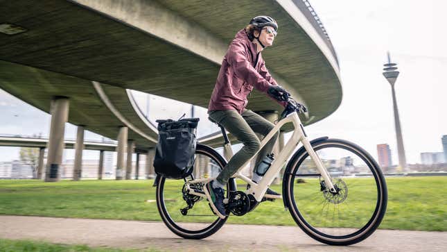 A photo of a person riding a cream-colored Orbea Diem electric bike in Düsseldorf. 