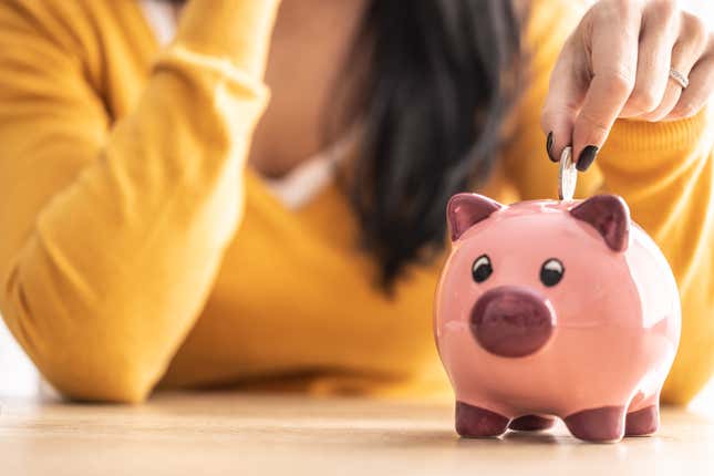 La mano de una mujer mete una moneda en una alcancía